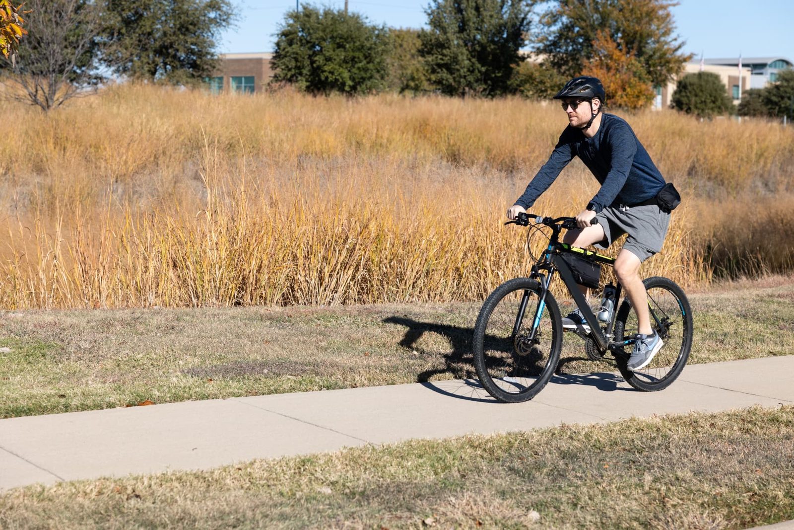 John B. Grimes riding a bicycle along an outdoor path.
